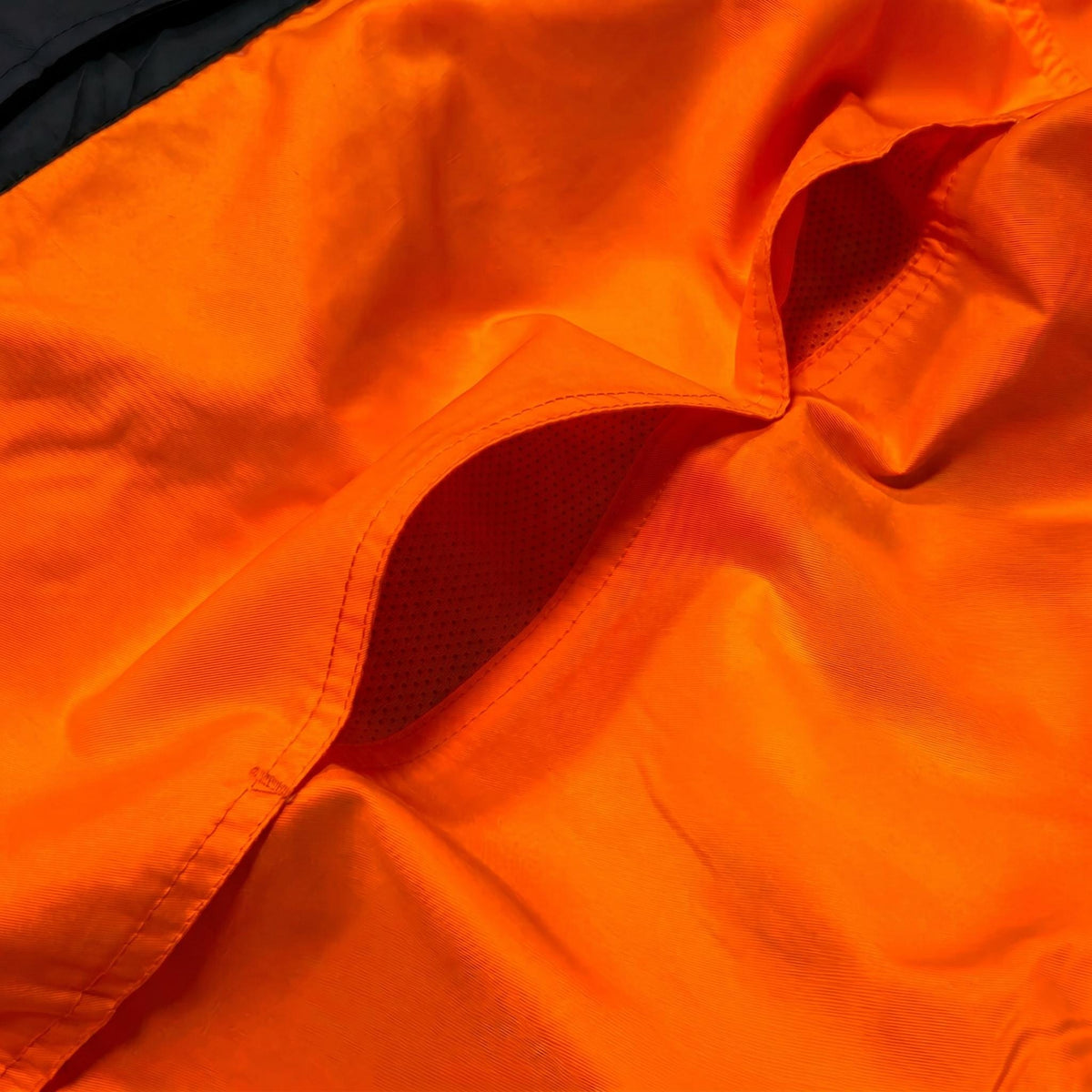Close-up of orange workwear pocket and mesh lining.